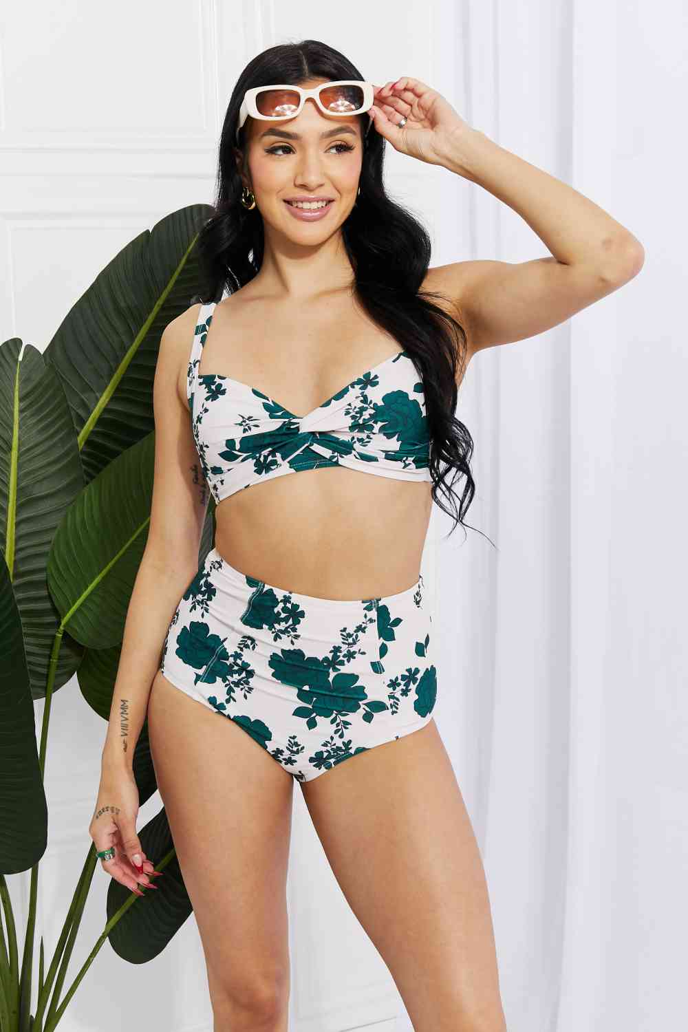 A high-waisted bikini featuring a twist-front top with removable padding, offering a customizable fit. The floral pattern and flattering high-rise bottoms make this Forest-colored swimsuit perfect for beach days.