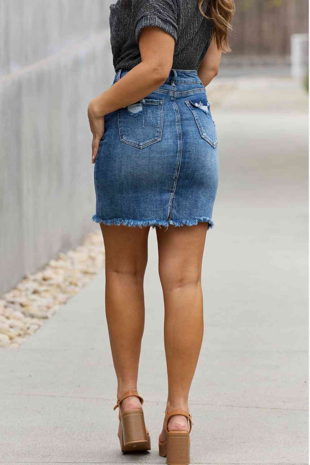 High-rise denim mini skirt with minimal distressing and a raw hem in medium wash.