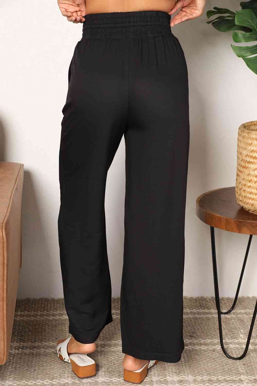 Black wide-leg pants with a drawstring-smocked waist.